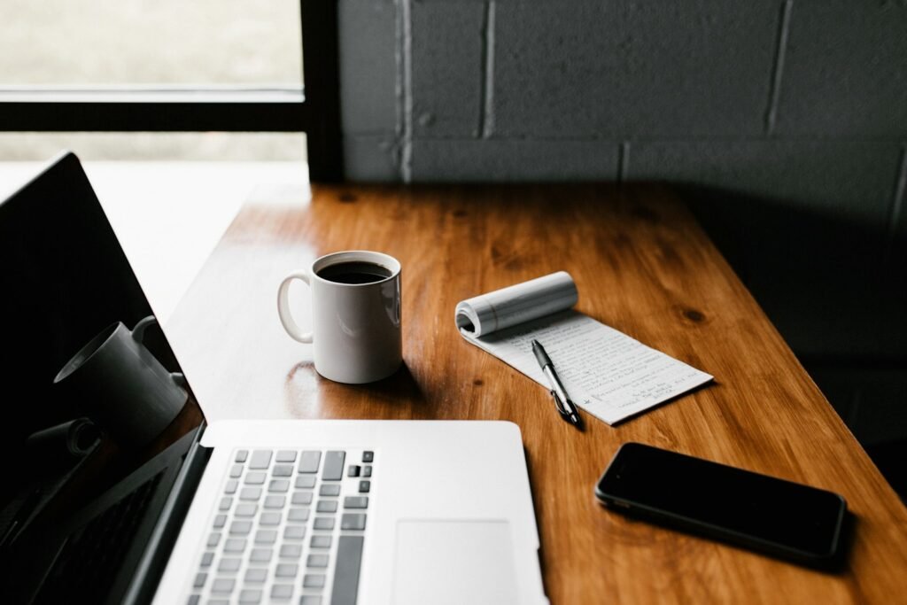 Laptop open on a wooden desk in a bright workspace