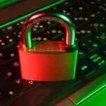 Red padlock resting on a black computer keyboard, representing cyber threat exposure