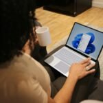 Microsoft Is Making Microsoft 365 Business with Copilot the New Small-Business Standard. Is It Worth It? Person working on a Microsoft laptop at a desk