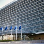 Modern glass building flying European Union flags
